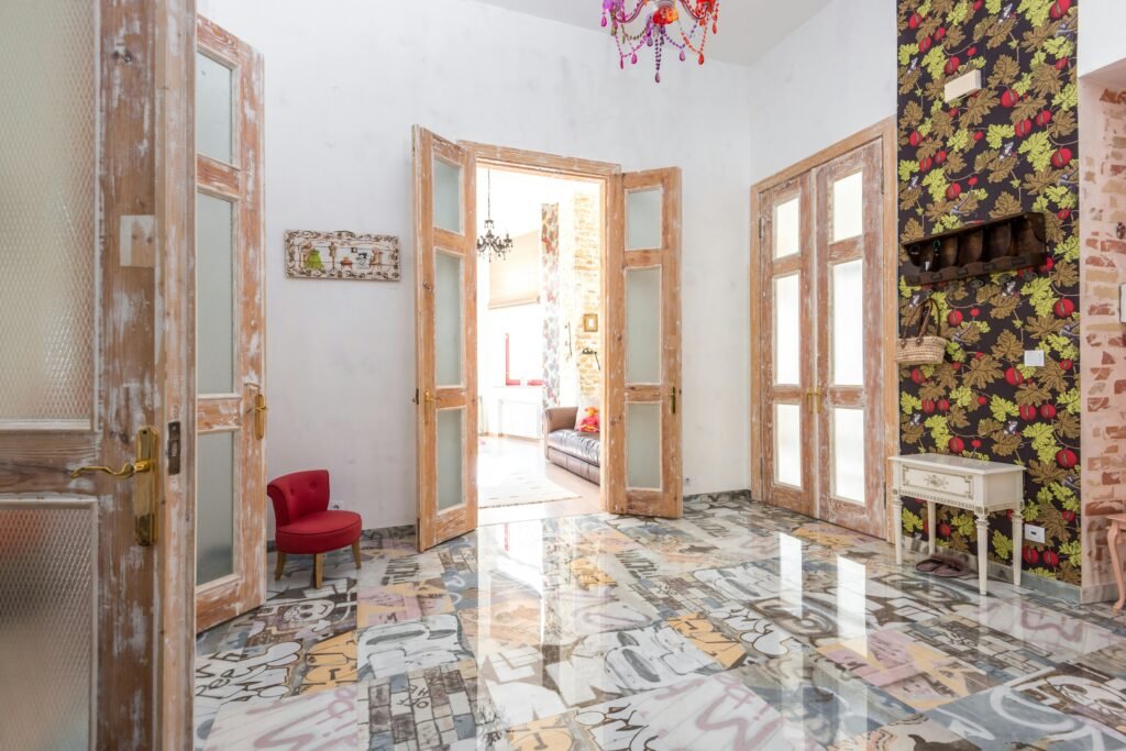 A vibrant, eclectic interior featuring colorful floors, wooden doors, and vivid wallpaper.